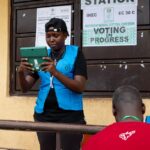Election official in Nigeria assisting voters on election day at a polling station.