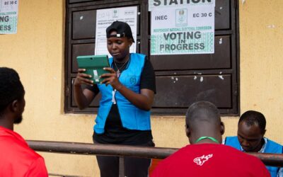 Election official in Nigeria assisting voters on election day at a polling station.